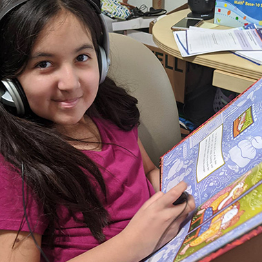 Girl using a headset and reading a book