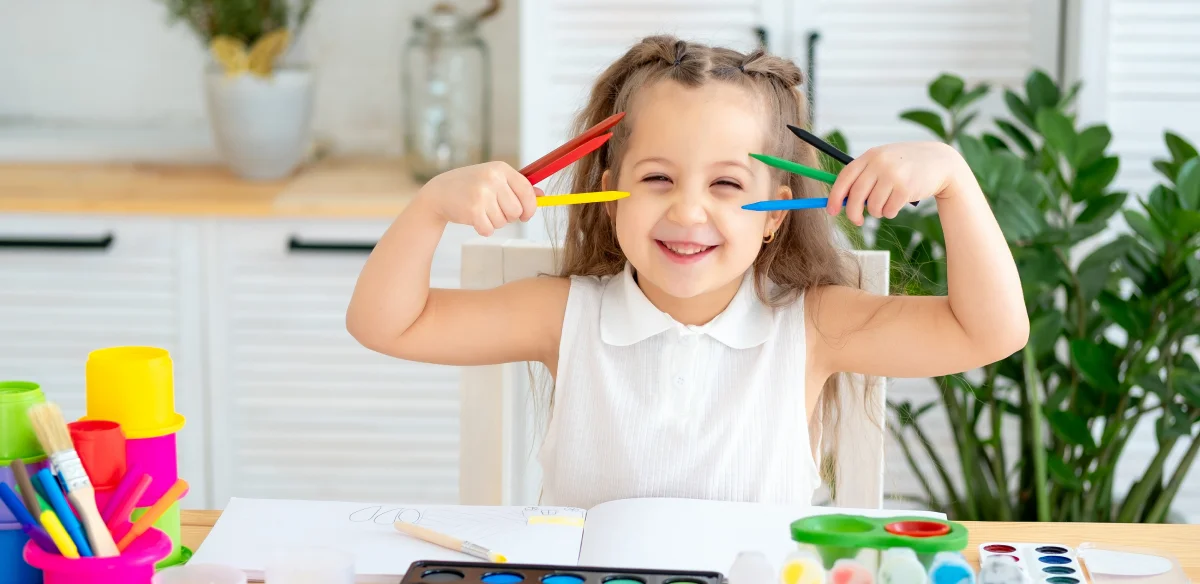 happy little girl with colors in her hands