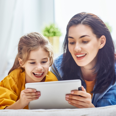 Mother and her daughter reading together with their tablet